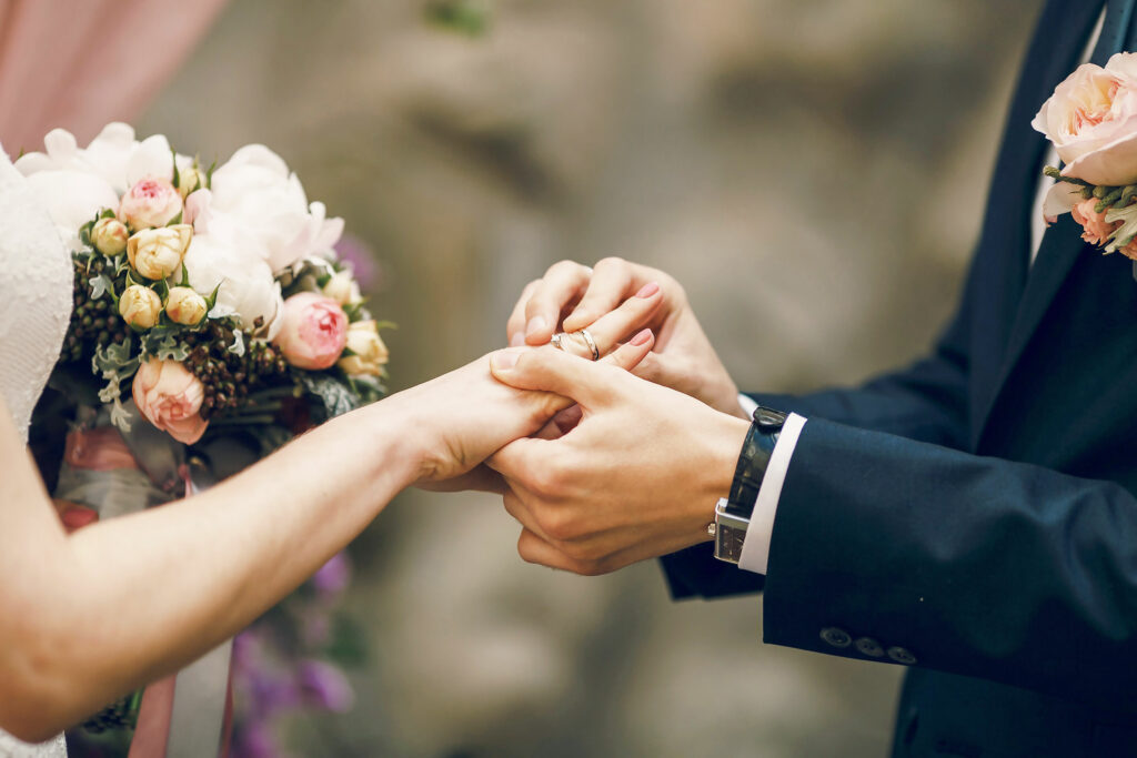 Groom putting ring on bride's finger