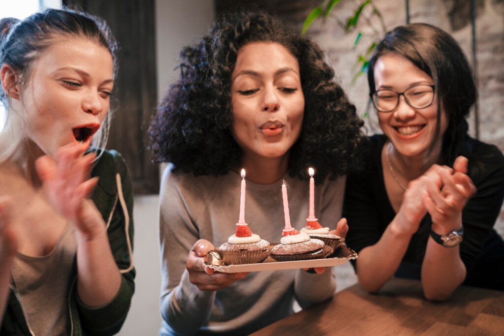 Friends blowing candles on birthday cake